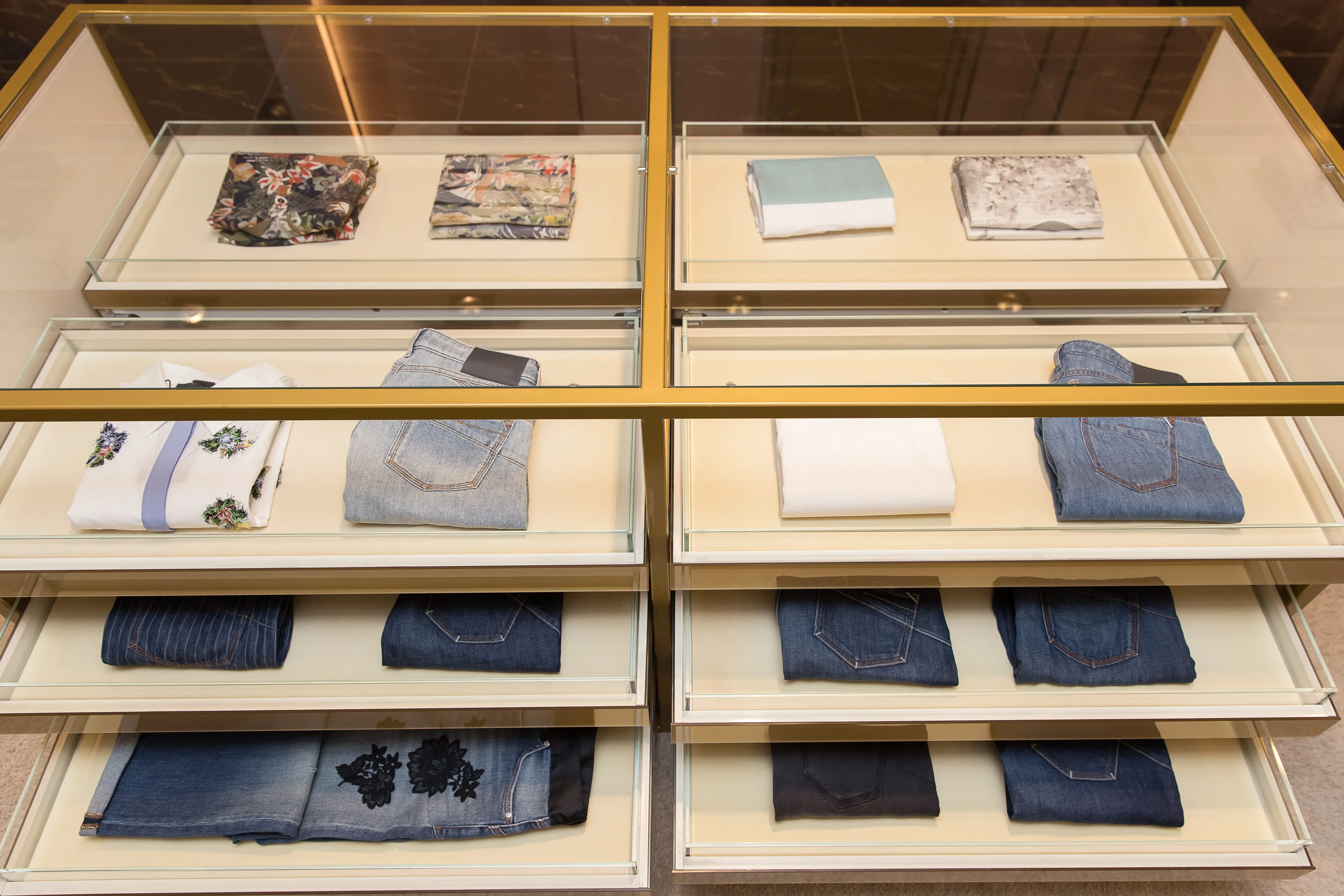 Ordentliche Stapel gefalteter Jeans und T-Shirts auf den Geschäftsregalen.